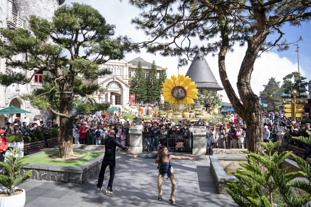 Màn biểu diễn nhảy múa tại Bà Nà Hills, Đà Nẵng, giữa đám đông và hoa hướng dương lớn.