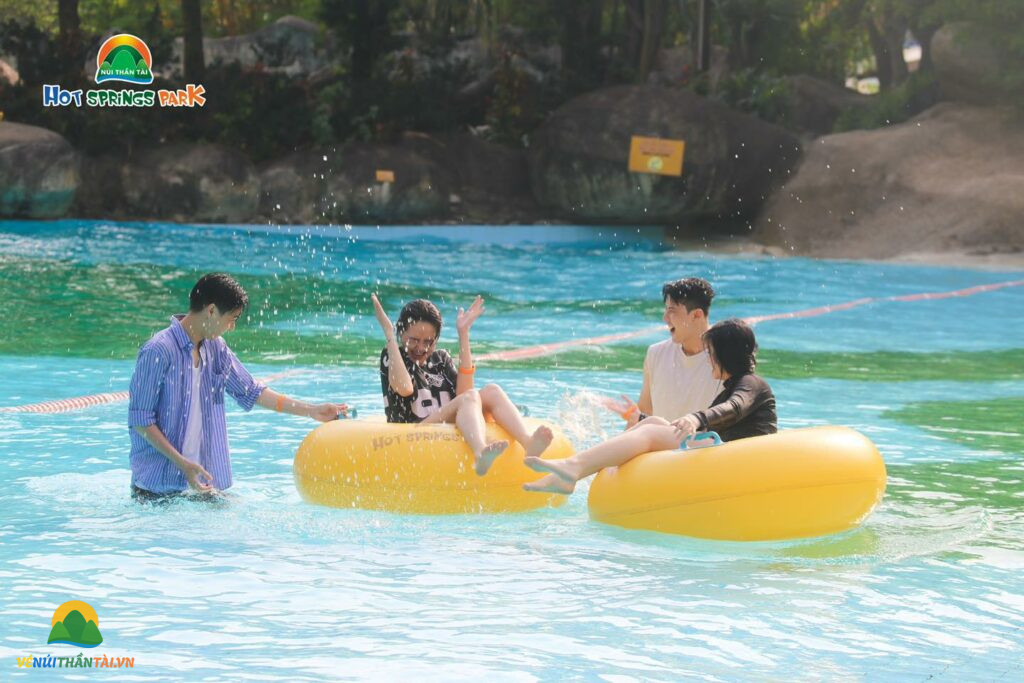 Du khách chơi đùa với những chiếc phao bơi vàng, tận hưởng thời gian thư giãn tại công viên suối khoáng nóng Núi Thần Tài.