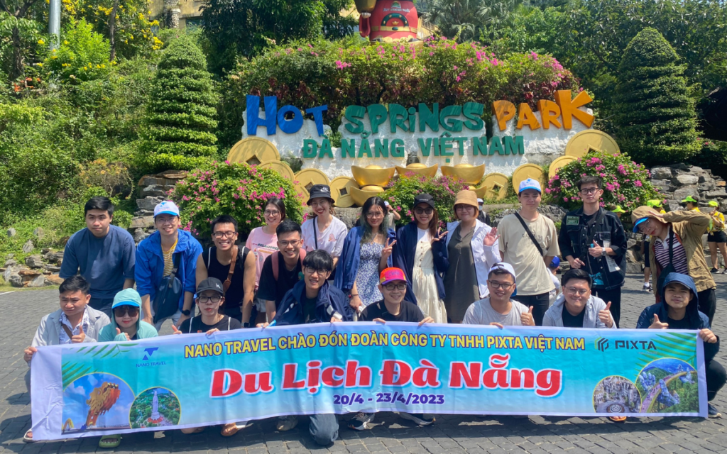 Nhóm du khách chụp ảnh tại công viên suối khoáng nóng Đà Nẵng, có biển hiệu "Hot Springs Park".